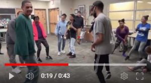 A video screen capture of students dancing in a circle.