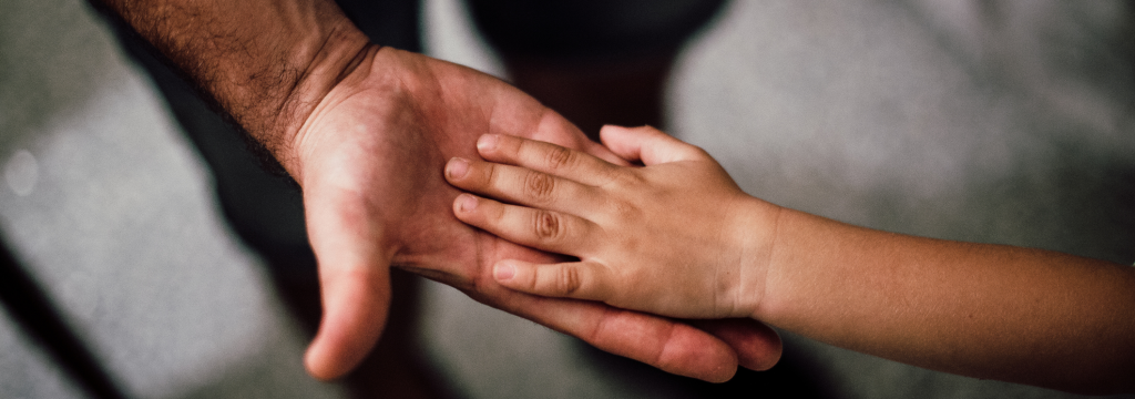 An child's hand rests in an adults hand