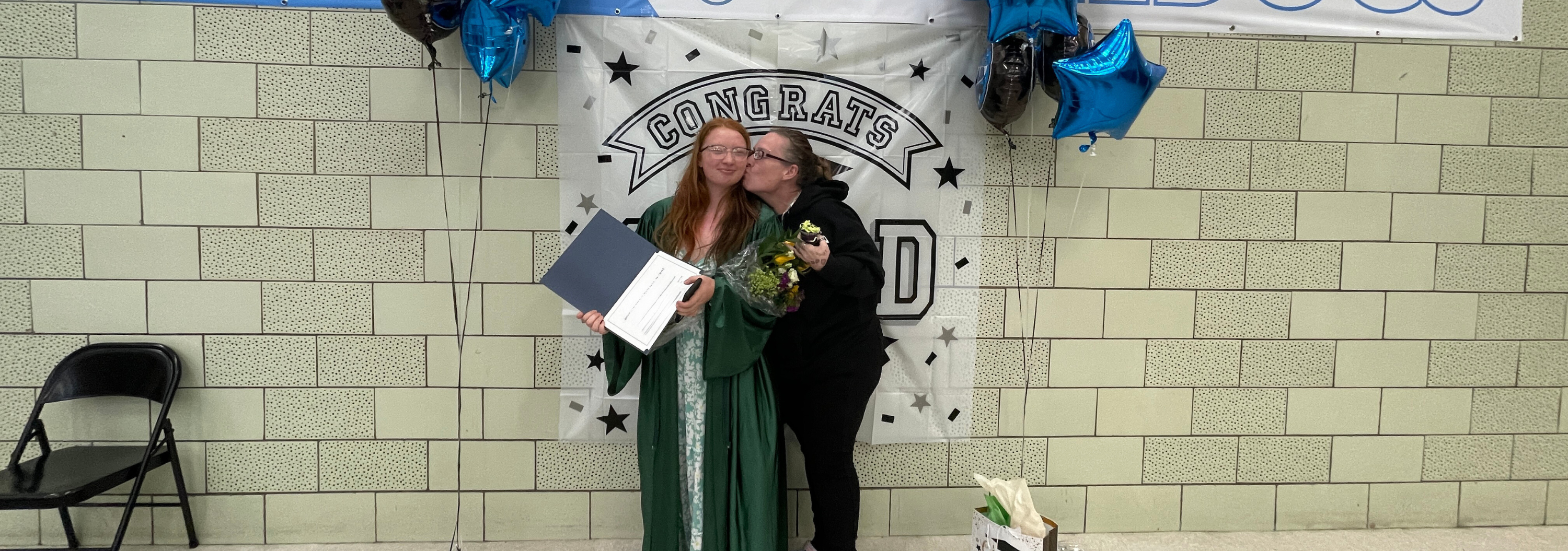 A caregiver hugs a graduate at graduation at PEP